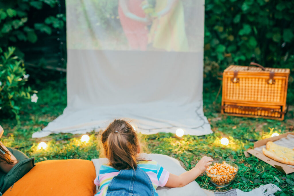 屋外で布のスクリーンで映画を見る少女